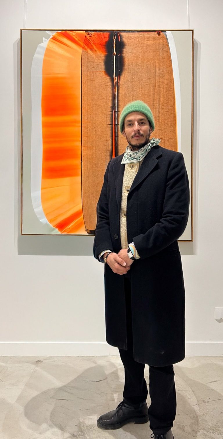 Fondateur de H.D Galerie, Hamza Djelassi posant devant une œuvre dans la galerie à Paris