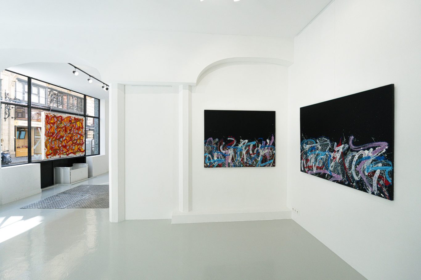 Ensemble de petites œuvres multicolores de JonOne alignées sur deux rangées sur un mur blanc.