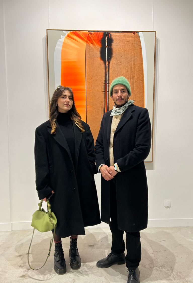 Clara Drogoul et Hamza Djelassi posant devant une œuvre d'art colorée.